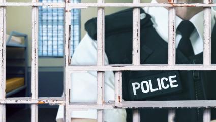 A policeman in uniform stood behind bars