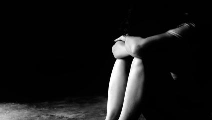 A woman hugging her knees with her head lowered