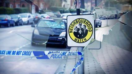 Smashed glass in front of a Neighbourhood Watch sign