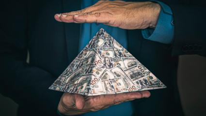 A man holding a pyramid made of US money