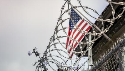 Barbed wire in front of a US flag at a prison