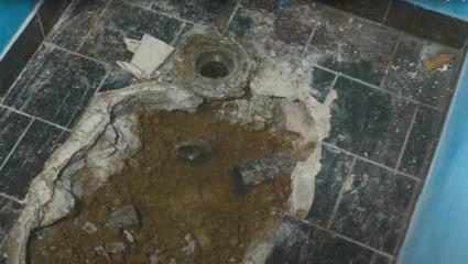 Exposed pipes under a tiled bathroom floor