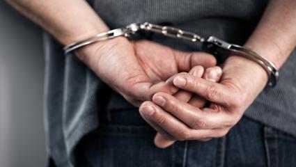 A man's hands handcuffed behind his back