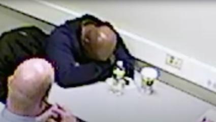 Robert Haskell with his head on his arms in the interrogation room