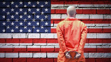 A prisoner in an orange jumpsuit with his hands cuffed behind his back