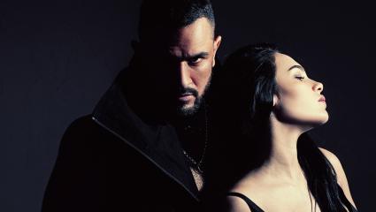 A man looks menacingly over a woman's shoulder at the camer