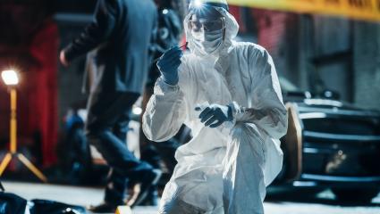 A photograph of a forensics specialist finding a bullet shell at a crime scene
