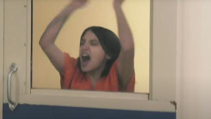 Woman banging on the window of a cell door