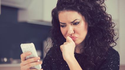 woman looks annoyed while reading a message