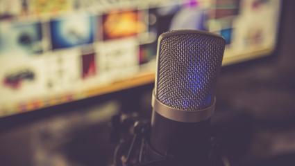 A podcast microphone in front of a laptop