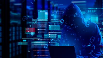 A hooded figure looks at a laptop surrounded by code and data warnings