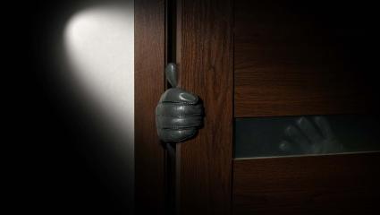 A gloved hand reaching around a door frame