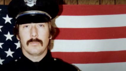 Drew Peterson in his police uniform stood in front of the United States flag