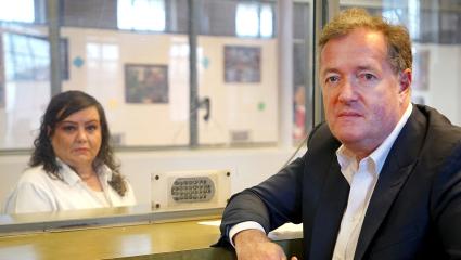 Piers Morgan posing with Kimberly Saenz on either side of a protective screen