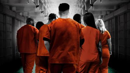 Prisoners wearing orange jumpsuits walking away from the camera