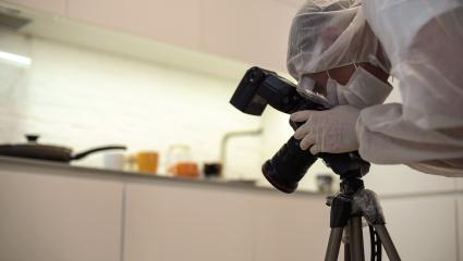 A crime scene photographer takes pictures in a kitchen