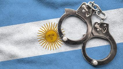A pair of police handcuffs on top of the Argentina flag