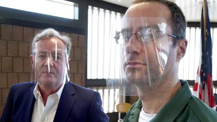 Piers Morgan standing with Christopher Porco - both are wearing clear plastic visors