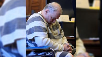 Richard Beasley sits in court in a wheelchair with his head slumped forwards