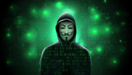 A hooded figure wearing an 'Anonymous' mask on a coded green background