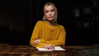 Laura Whitmore wearing a yellow jumper and sitting at a large table