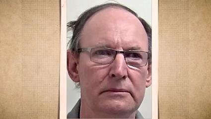 A mugshot of an David Fuller with thinning hair and glasses, wearing a neutral expression against a plain light-coloured background.