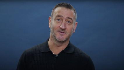 Will Mellor standing in front of a blue background