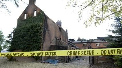 The burnt out Foster family mansion with yellow police tape in front of it
