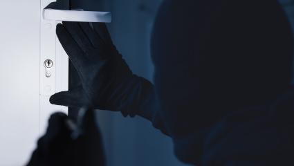 A man looks to pick the lock of a front door
