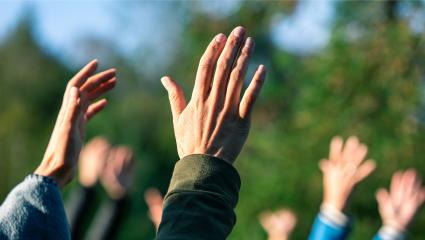 A group of people standing outside with their hands in the air