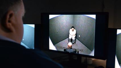 A man watching a police interrogation on a screen