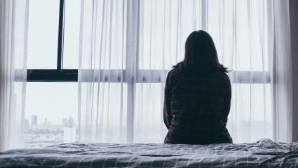 A woman sitting on a bed looking out of the window