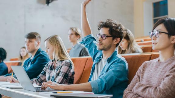 Student raises his hand while in a lecture
