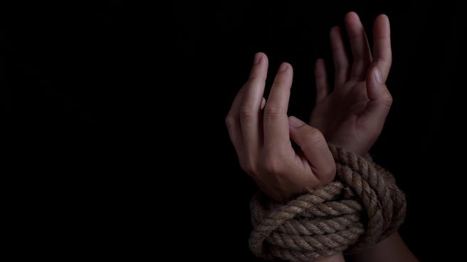 Stock image of a woman's wrists tied with rope