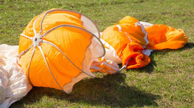 A discarded skydiving parachute on the floor in a field