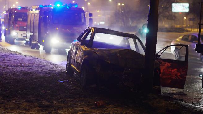 A car crashed into a post with fire engines in the background
