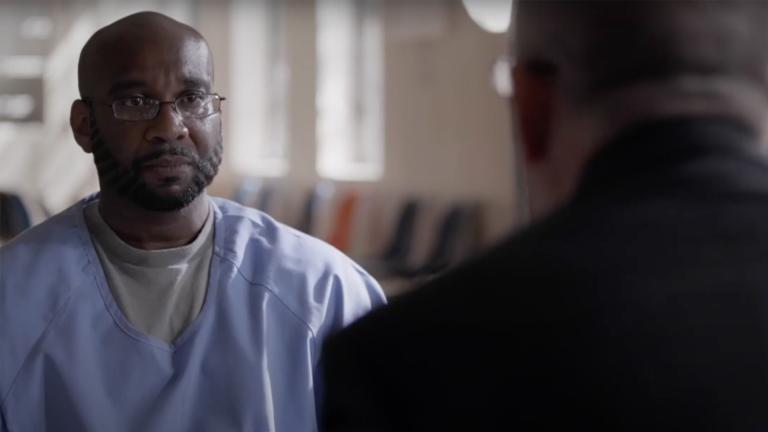 A prisoner listens as a man opposite him speaks