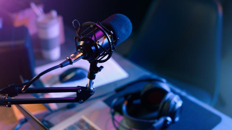 A podcast microphone with headphones on the desk