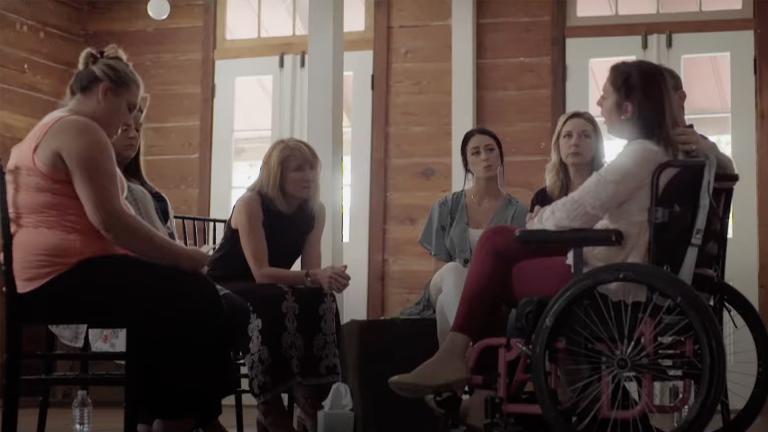 Adults sat in a circle with a young woman in a wheelchair