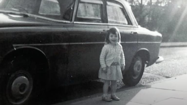 Alissa Moore as a young girl stood in front of a car