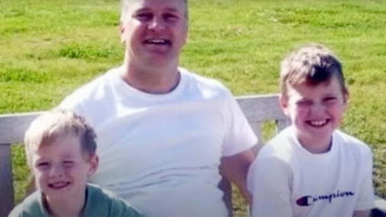 Darren Sykes sitting on a park bench with his sons, Jack and Paul