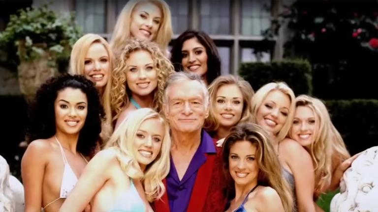 An old Hugh Hefner posing with Playboy models