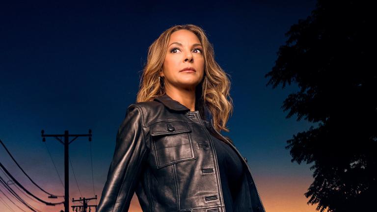 Eva Larue in black leather jacket stands against a dark street backdrop