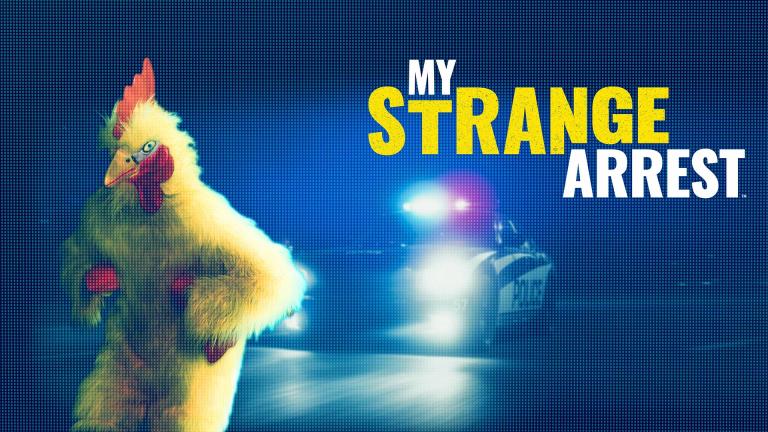 A man in a chicken costume runs away from a police car