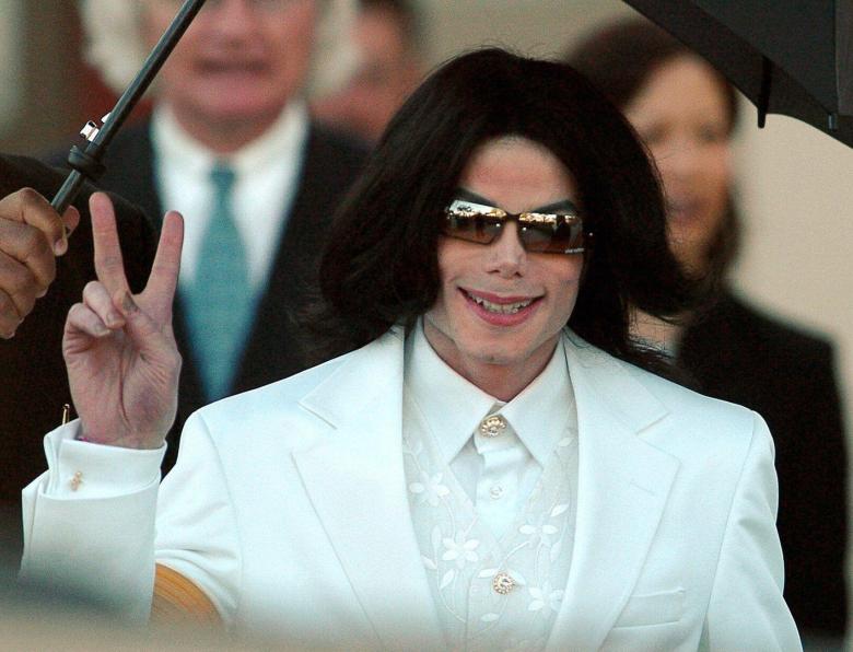 Michael Jackson flashes the 'Peace' sign to crowds of supporters as he arrives at court