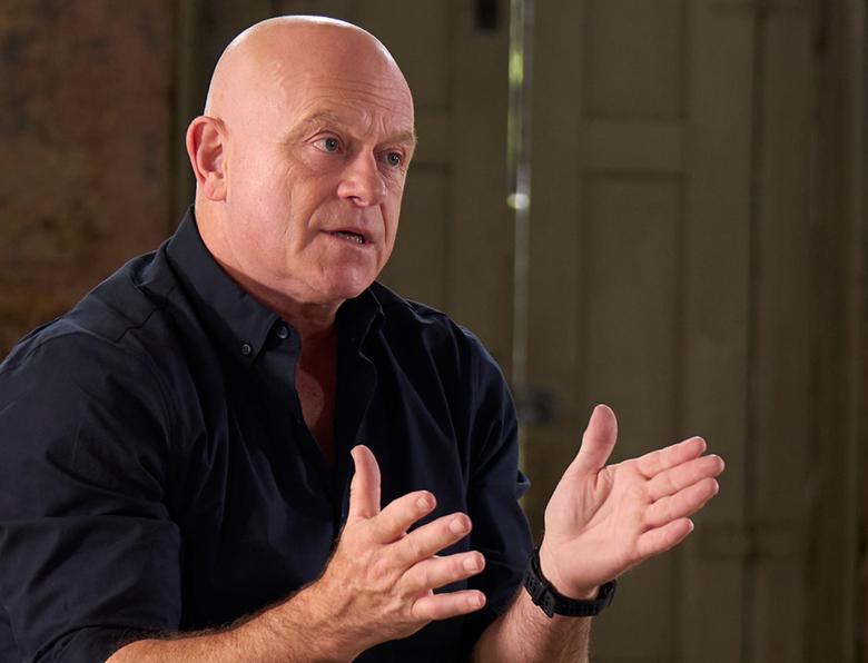 Ross Kemp gestures with his hands while talking to someone out of frame
