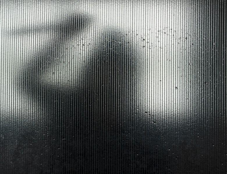 Silhouette of someone wielding a knife behind frosted glass