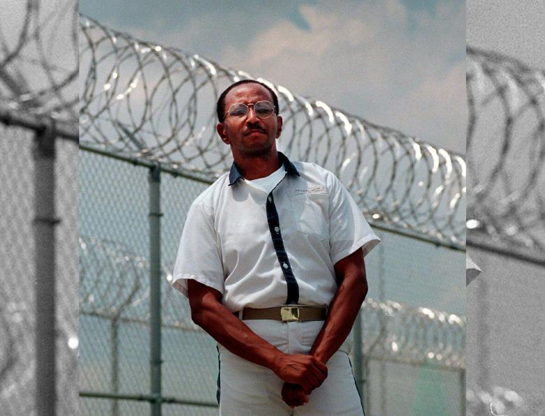 Wayne Williams poses along the fence line of a prison in a 1999 file photo
