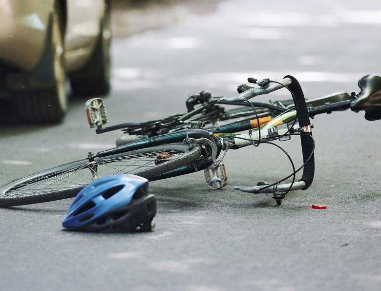 A bike and helmet lying on the road after being hit by a car