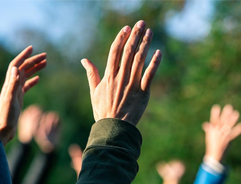 A group of people standing outside with their hands in the air